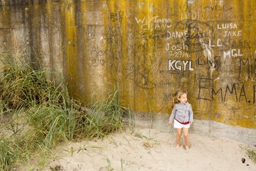 Caucasian girl standing in sand near graffiti wall - BLEF01049