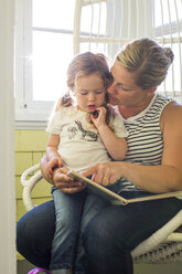 Caucasian mother reading book to daughter on lap - BLEF01070