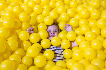 Caucasian girl laying in pile of yellow balls - BLEF01073