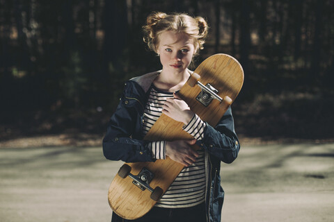 Porträt eines kaukasischen Teenagers mit Skateboard, lizenzfreies Stockfoto