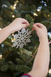 Kaukasisches Mädchen hängt Schneeflocke Ornament auf Weihnachtsbaum - BLEF01095