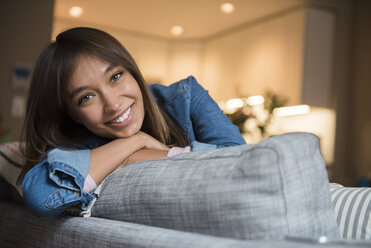 Smiling Mixed Race woman leaning on sofa - BLEF01105