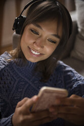 Mixed Race woman listening to cell phone with headphones - BLEF01106