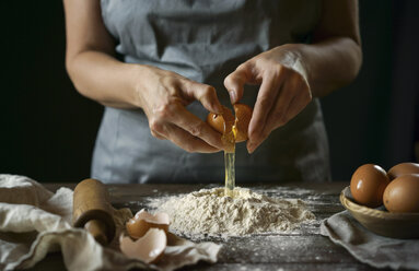 Caucasian woman cracking egg over flour - BLEF01162