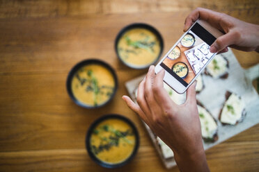 Hände einer Bloggerin beim Fotografieren von Kürbissuppe und Knäckebrot mit dem Smartphone im Kreativbüro - MASF11899