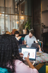 Young female professional using mobile phone while sitting with laptop at creative office - MASF11925