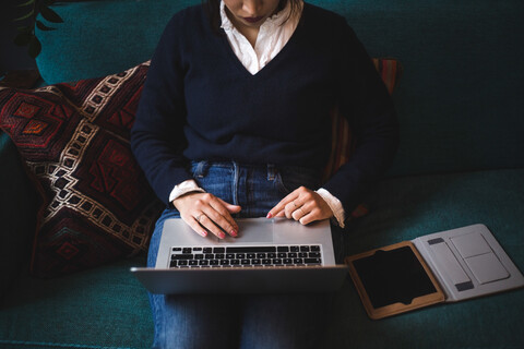 Midsection von weiblichen professionellen mit Laptop sitzen auf dem Sofa im Büro, lizenzfreies Stockfoto