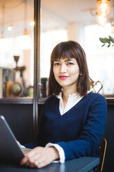 Porträt einer selbstbewussten weiblichen Fachkraft, die mit einem Laptop im Büro sitzt - MASF11971