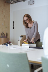 Mid adult female executive examining files on conference table at office - MASF11974