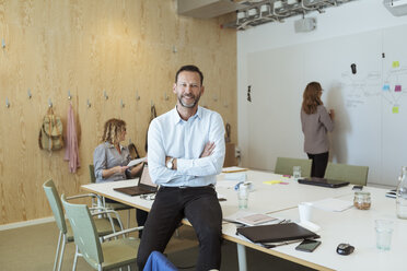 Porträt eines zuversichtlich lächelnden Geschäftsmannes mit Kollegen im Sitzungssaal eines Büros - MASF11992