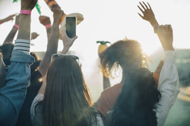 Frau hält Smartphone, während sie mit Freunden ein Musikfestival genießt - MASF12042