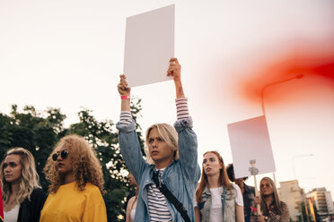 Junge Männer und Frauen protestieren mit Plakaten bei einer Demonstration gegen den Himmel in der Stadt - MASF12067