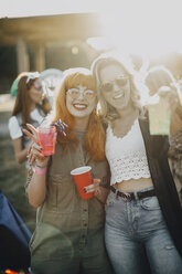Portrait of happy friends enjoying drinks in music festival on sunny day - MASF12080