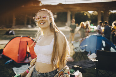 Porträt einer lächelnden jungen Frau mit Sonnenbrille auf einem Musikfestival - MASF12102