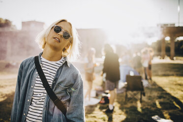 Portrait of young confident man wearing sunglasses standing in music festival - MASF12104