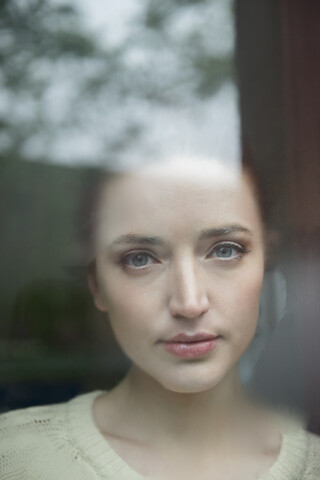 Ernste kaukasische Frau hinter nebligem Fenster, lizenzfreies Stockfoto