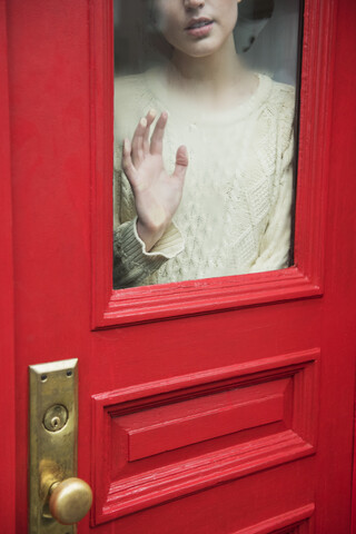 Caucasian woman daydreaming behind red door stock photo