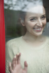 Kaukasische Frau lächelt hinter einem nebligen Fenster - BLEF01177