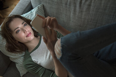 Caucasian woman laying on sofa texting on cell phone - BLEF01179