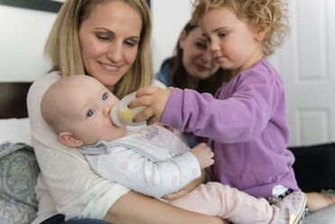 Kaukasisches Mädchen füttert ihre kleine Schwester mit der Flasche - BLEF01213