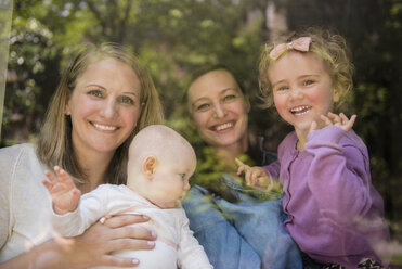 Caucasian mothers and daughters waving behind window - BLEF01214