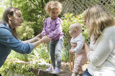 Caucasian mothers holding daughters on garden wall - BLEF01217