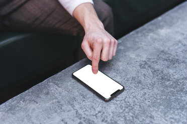 Nahaufnahme eines Mannes, der auf einem Handydisplay tippt - FBAF00437