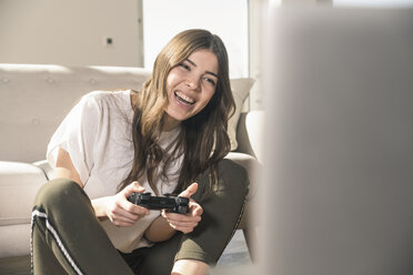 Glückliche junge Frau spielt ein Videospiel zu Hause - UUF17250