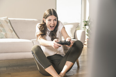 Glückliche junge Frau spielt ein Videospiel zu Hause, lizenzfreies Stockfoto