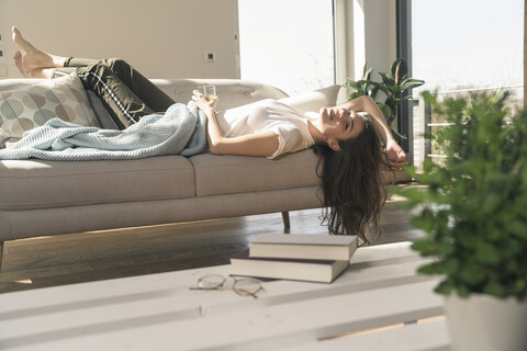 Entspannte junge Frau auf Couch liegend, lizenzfreies Stockfoto