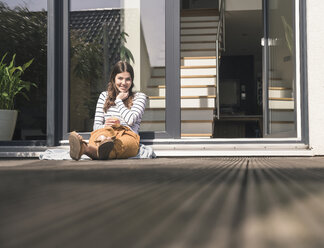 Young woman sitting on terrace at home - UUF17289