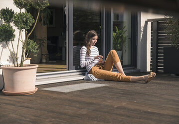 Young woman sitting on terrace at home - UUF17290