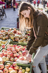 Mädchen mit Stofftasche beim Aussuchen von Äpfeln auf dem Wochenmarkt - STBF00299