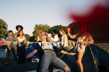 Young friends performing limbo dance while camping in music festival - MASF12158