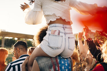 Mann, der seinen Freund auf der Schulter trägt, während er sich auf einem Musikfestival vergnügt - MASF12171