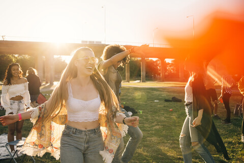 Happy young woman dancing with friends on sunny day in music event stock photo