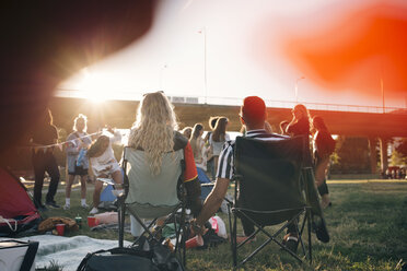 Rückansicht eines Mannes und einer Frau, die sich auf Stühlen sitzend bei einem Musikfestival an den Händen halten - MASF12194