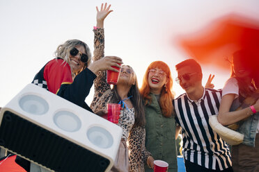 Glückliche Freunde mit Lautsprecher und Getränken genießen in Musikfestival gegen Himmel - MASF12196