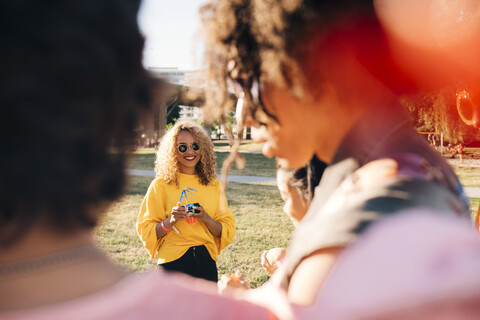 Lächelnde Frau mit Freunden, die ein Konzert an einem sonnigen Tag genießen, lizenzfreies Stockfoto