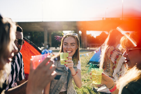 Lächelnde Freunde, die im Sommer bei einem Musikkonzert Getränke genießen - MASF12229