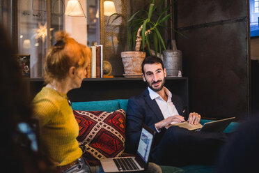 Confident male and female business colleagues discussing on sofa at creative office - MASF12240