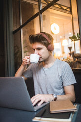 Selbstbewusster Geschäftsmann, der Kaffee trinkt, während er einen Laptop am Schreibtisch im Büro benutzt - MASF12244