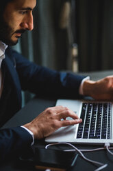 Confident businessman typing on laptop at desk in creative office - MASF12253