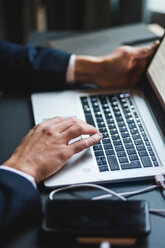 Hands of businessman typing on laptop keyboard at desk in creative office - MASF12254