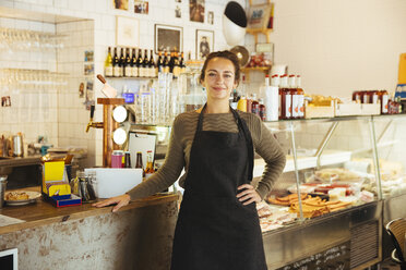 Porträt einer selbstbewussten jungen Besitzerin, die in einem Café steht und die Hand auf die Hüfte legt - MASF12259