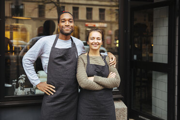 Portrait of confident young owners standing against delicatessen window in city - MASF12282