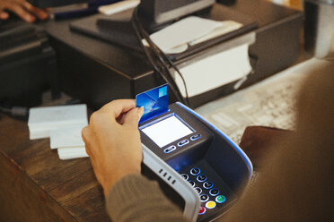 High angle view of customer paying through credit card at checkout counter in delicatessen - MASF12285