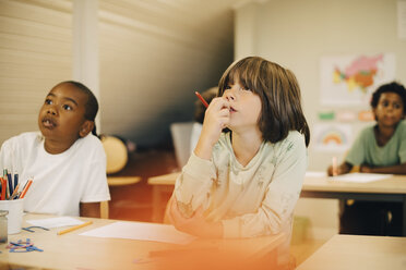 Männliche Schüler, die sich am Schreibtisch im Klassenzimmer konzentrieren - MASF12289