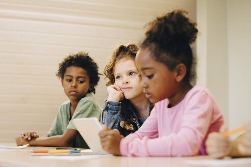 Männliche und weibliche Schüler betrachten ein digitales Tablet im Klassenzimmer - MASF12299