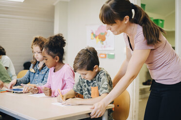 Female teacher assisting students in learning at classroom - MASF12306